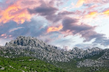 Kayalık dağ manzarası ve zıt bulutlu gökyüzü. Hırvatistan