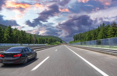 Asfalt yolda siyah bir araba. Güzel günbatımında asfalt yol manzarası kırsalda