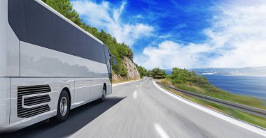 Deniz kıyısındaki bir dağ yolunda turist otobüsü. Turist seyahat kavramı.