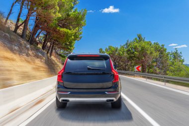 Mavi araba güneşli bir yaz gününde deniz kıyısı boyunca yol alır..