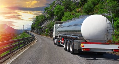 Yakıt kamyonu güzel bir yolda. Gümüş bir tank kamyonu yakıt taşıyor..