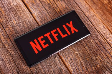 Uzhgorod, Ukrayna - 2 Eylül 2020: Netflix programı ahşap bir masada uzanan siyah bir akıllı telefonda açık.