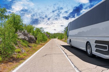 Beyaz bir turist otobüsü pitoresk bir dağ yolunda ilerliyor..