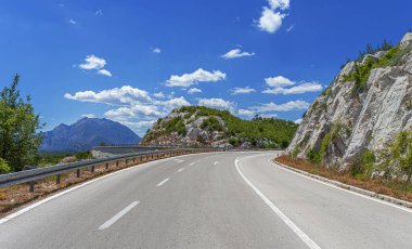Arka planda kayalık dağlar olan köy yolu..