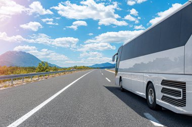 Beyaz bir turist otobüsü pitoresk bir dağ yolunda ilerliyor..