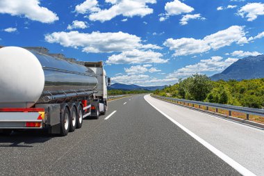 Yakıt kamyonu güzel bir yolda. Gümüş bir tank kamyonu yakıt taşıyor..