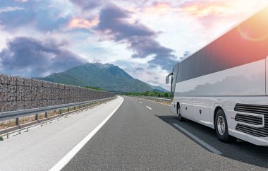 Beyaz bir turist otobüsü pitoresk bir dağ yolunda ilerliyor..