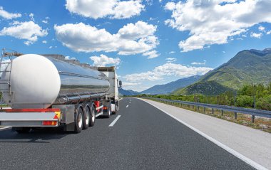 Yakıt kamyonu güzel bir yolda. Gümüş bir tank kamyonu yakıt taşıyor..