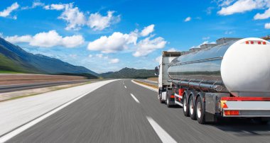 Yakıt kamyonu güzel bir yolda. Gümüş bir tank kamyonu yakıt taşıyor..
