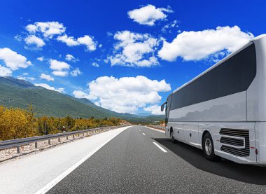 Beyaz bir turist otobüsü pitoresk bir dağ yolunda ilerliyor..