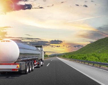 Yakıt kamyonu güzel bir yolda. Gümüş bir tank kamyonu yakıt taşıyor..