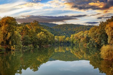 Sonbahar ormanının arka planındaki göl gün batımının ışınlarında.