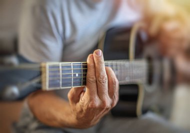 Bir adam gitar çalıyor, yakın planda çekilmiş..