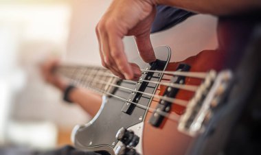 Bir adam gitar çalıyor, yakın planda çekilmiş..