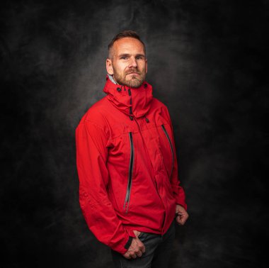 Siyah arka planda kırmızı spor ceketli yakışıklı bir genç..