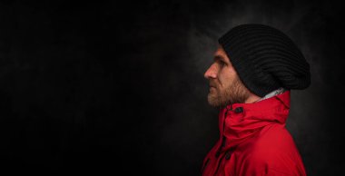 Siyah arka planda spor ceketli ve spor şapkalı yakışıklı bir genç..