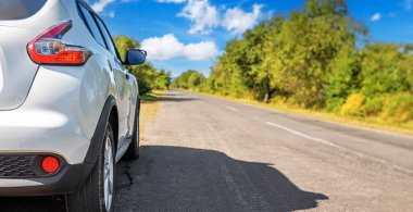 Bir otoyolun kenarına beyaz bir araba park edilmiş..