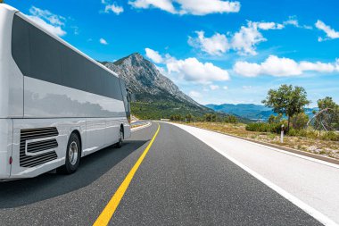 Beyaz bir turist otobüsü pitoresk bir dağ yolunda ilerliyor..