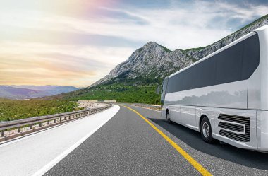 Beyaz bir turist otobüsü pitoresk bir dağ yolunda ilerliyor..