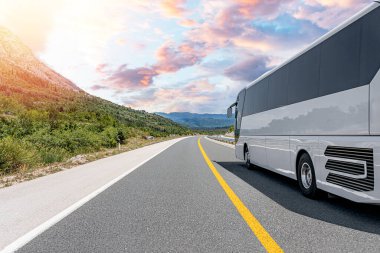 Beyaz bir turist otobüsü pitoresk bir dağ yolunda ilerliyor..