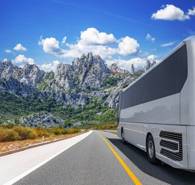 Beyaz bir turist otobüsü pitoresk bir dağ yolunda ilerliyor..