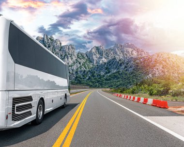 Beyaz bir turist otobüsü pitoresk bir dağ yolunda ilerliyor..