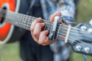 Arkaplanda akustik gitarlı bir erkek eli var..