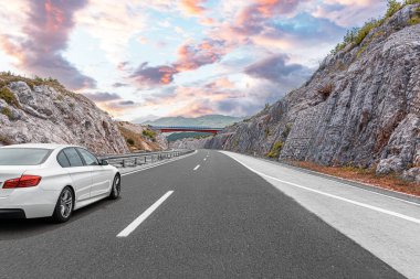 Araba otoban boyunca sürüyor. Etrafı resimlerle çevrili..