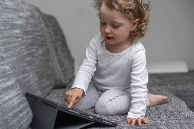 Rahat bir evde tablet kullanan küçük bir kız. Rahat bir evde tabletle oynayan küçük bir çocuk..