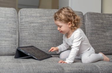Rahat bir evde tablet kullanan küçük bir kız. Rahat bir evde tabletle oynayan küçük bir çocuk..