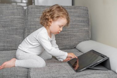 Rahat bir evde tablet kullanan küçük bir kız. Rahat bir evde tabletle oynayan küçük bir çocuk..