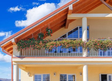 Güzel bir kır evi, rahat bir terası ve canlı kırmızı sardunyalarla süslenmiş bir balkonu var..