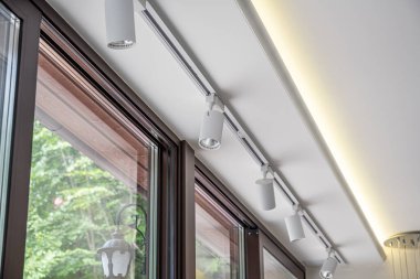 Ayarlanabilir beyaz spot ışıklarına sahip modern bir ray aydınlatma sistemi tavana zarif bir şekilde monte edilmiş ve odaklanmış aydınlatma sağlıyor..