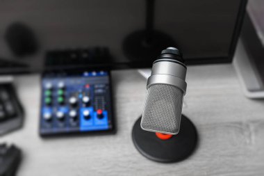 Bir masaüstü standında profesyonel bir yoğunlaştırıcı mikrofon, bir bilgisayar monitörü, klavye ve oyun çevresiyle çevrili, modern bir oyun ve kayıt çalışma istasyonunda kurulur..