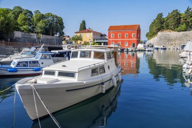 Renkli tarihi binalar, demirlemiş tekneler ve sakin bir rıhtım ile eski dünya cazibesini, parlak mavi gökyüzü altında modern elementlerle harmanlayan görkemli bir Akdeniz limanı..