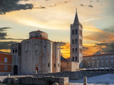 Hırvatistan 'ın tarihi eski Zadar kasabasında, gün batımında St. Anastasia Katedrali' nin çan kulesi ve St. Donatus Kilisesi 'nin çarpıcı manzarası.