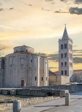 Hırvatistan 'ın tarihi eski Zadar kasabasında, gün batımında St. Anastasia Katedrali' nin çan kulesi ve St. Donatus Kilisesi 'nin çarpıcı manzarası.