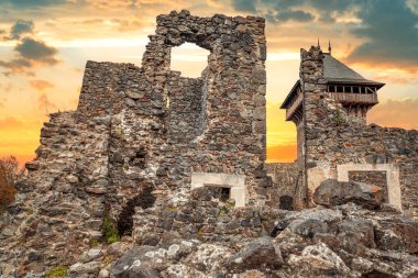 Nevytsky Şatosu, Ukrayna 'nın Uzhhorod yakınlarındaki yeşil bir yamaçta parlayan bir günbatımı gökyüzüne karşı duran ortaçağ kalıntısı..