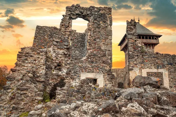 Nevytsky Şatosu, Ukrayna 'nın Uzhhorod yakınlarındaki yeşil bir yamaçta parlayan bir günbatımı gökyüzüne karşı duran ortaçağ kalıntısı..