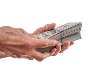 Yaşlı bir insan, temiz beyaz bir arkaplan karşısında zenginliği, tasarrufu ya da finansal değişimi simgeleyen kalın bir yığın 100 dolarlık banknot tutuyor..