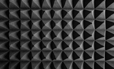 Siyah akustik köpük paneller, ses emmek ve stüdyo ortamlarında yankıyı azaltmak için tasarlanmış keskin, geometrik bir desen şeklinde düzenlenmiştir..