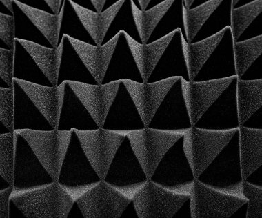Siyah akustik köpük paneller, ses emmek ve stüdyo ortamlarında yankıyı azaltmak için tasarlanmış keskin, geometrik bir desen şeklinde düzenlenmiştir..