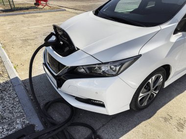 Bir elektrik aracı, ön montajlı şarj limanı ve ağır güç kablosu üzerinden bir istasyonda şarj ediliyor..