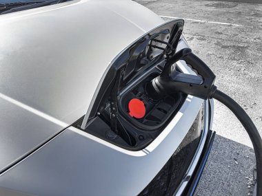 Bir elektrik aracı, ön montajlı şarj limanı ve ağır güç kablosu üzerinden bir istasyonda şarj ediliyor..