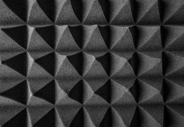 Siyah akustik köpük paneller, ses emmek ve stüdyo ortamlarında yankıyı azaltmak için tasarlanmış keskin, geometrik bir desen şeklinde düzenlenmiştir..