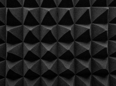 Siyah akustik köpük paneller, ses emmek ve stüdyo ortamlarında yankıyı azaltmak için tasarlanmış keskin, geometrik bir desen şeklinde düzenlenmiştir..