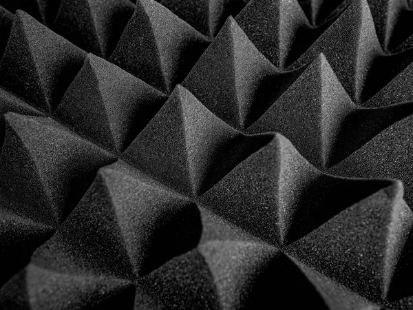 Siyah akustik köpük paneller, ses emmek ve stüdyo ortamlarında yankıyı azaltmak için tasarlanmış keskin, geometrik bir desen şeklinde düzenlenmiştir..