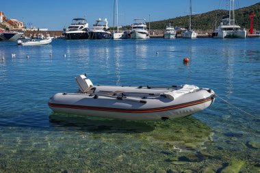 Hırvatistan 'ın Primosten kentindeki kristal berrak Adriyatik sularında küçük şişme bir tekne, limanda demirlemiş lüks yatlarla sakince yüzüyor.