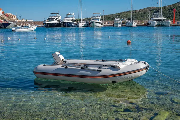 Hırvatistan 'ın Primosten kentindeki kristal berrak Adriyatik sularında küçük şişme bir tekne, limanda demirlemiş lüks yatlarla sakince yüzüyor.