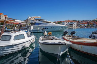 Birçok lüks yat ve tekne, sakin deniz ve uzak yeşil kıyı şeridi ile çevrili güneşli bir marinada demirlemiştir.